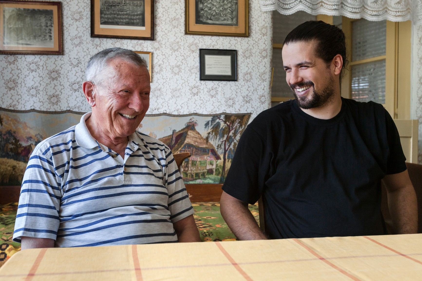 An older man and his adult son sharing a laugh at home